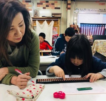 小林先生と生徒がそろばんに打ち込んでいます。授業は15人までの少人数制